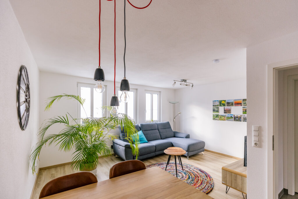 Sonniger Wohn-Essraum mit Pendelleuchten, Palme und Region-Fotowand