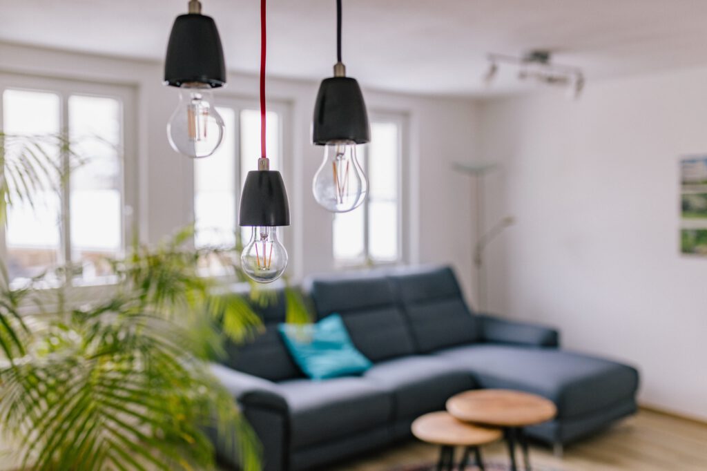 Wohnzimmer im Ferienhaus Alte Pfarrgasse 13 mit blauem Ecksofa, Pendelleuchten und Zimmerpalme