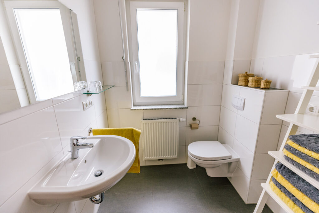 Badezimmer der Ferienwohnung Alte Pfarrgasse 5 mit Waschbecken, Spiegel, Fenster und Wand-WC