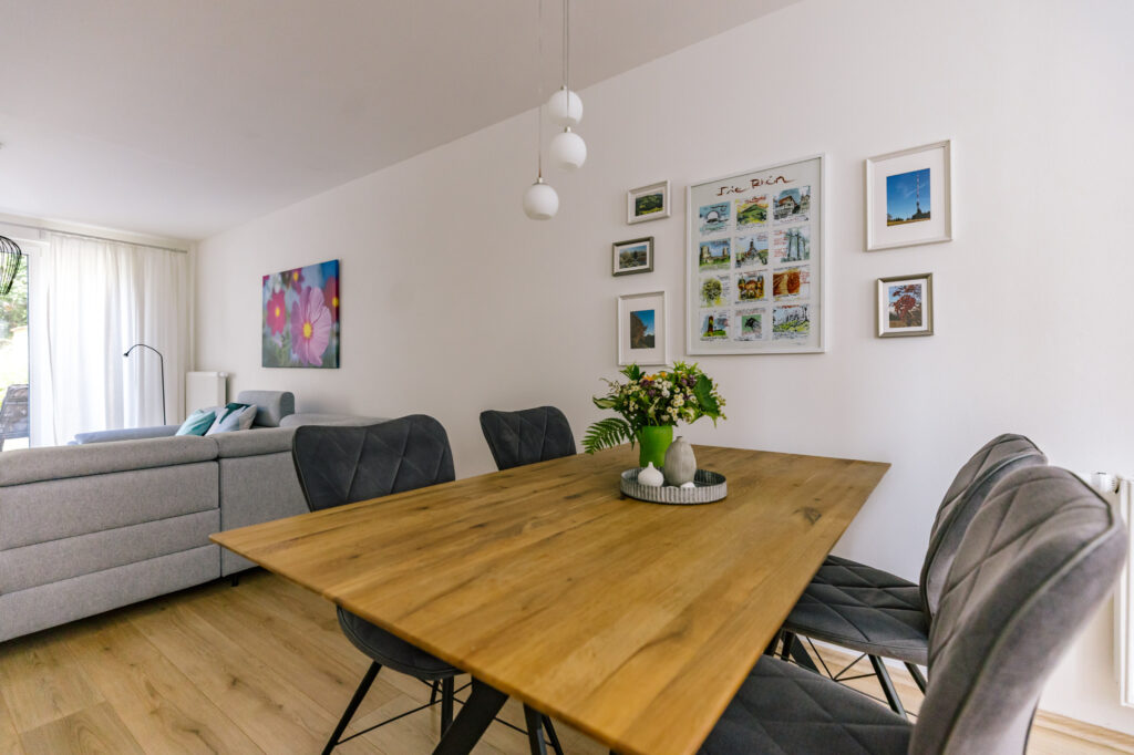 Essplatz für sechs Personen in der Ferienwohnung Alte Pfarrgasse 5 mit Massivholztisch, Polsterstühlen und Blumenstrauß