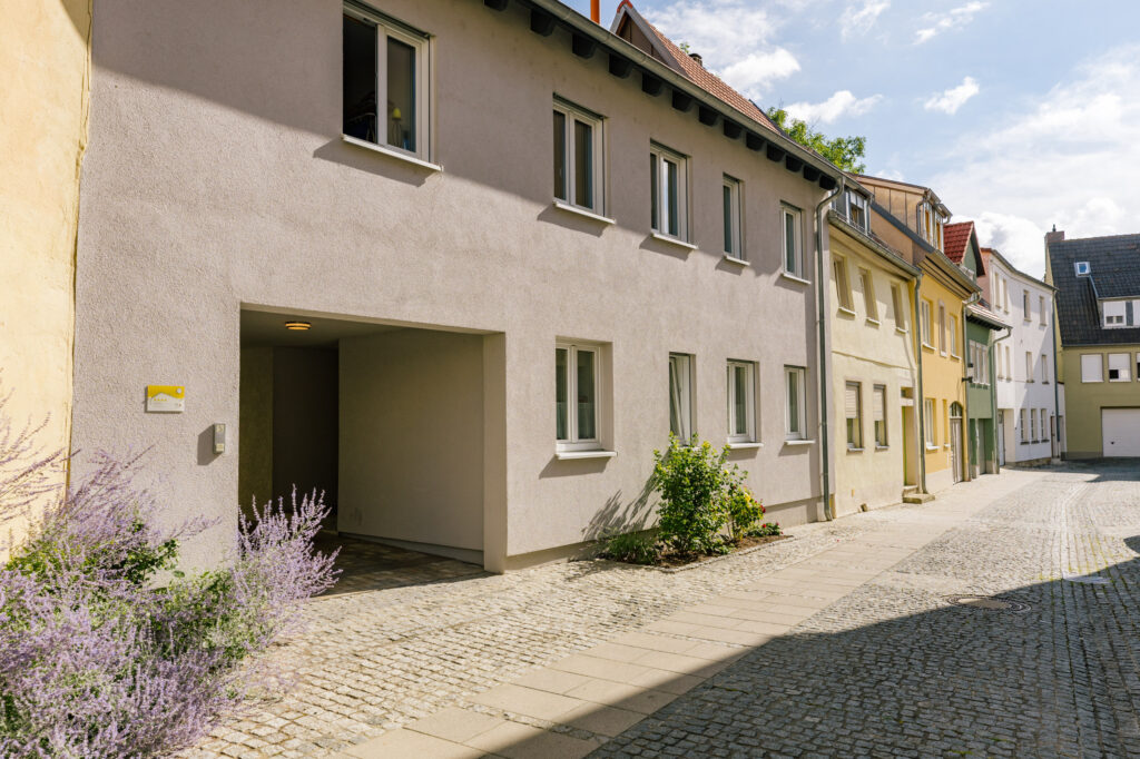 Hausfront der Ferienwohnung Alte Pfarrgasse 5 mit Durchfahrt und blühendem Lavendel an der gepflasterten Altstadtgasse
