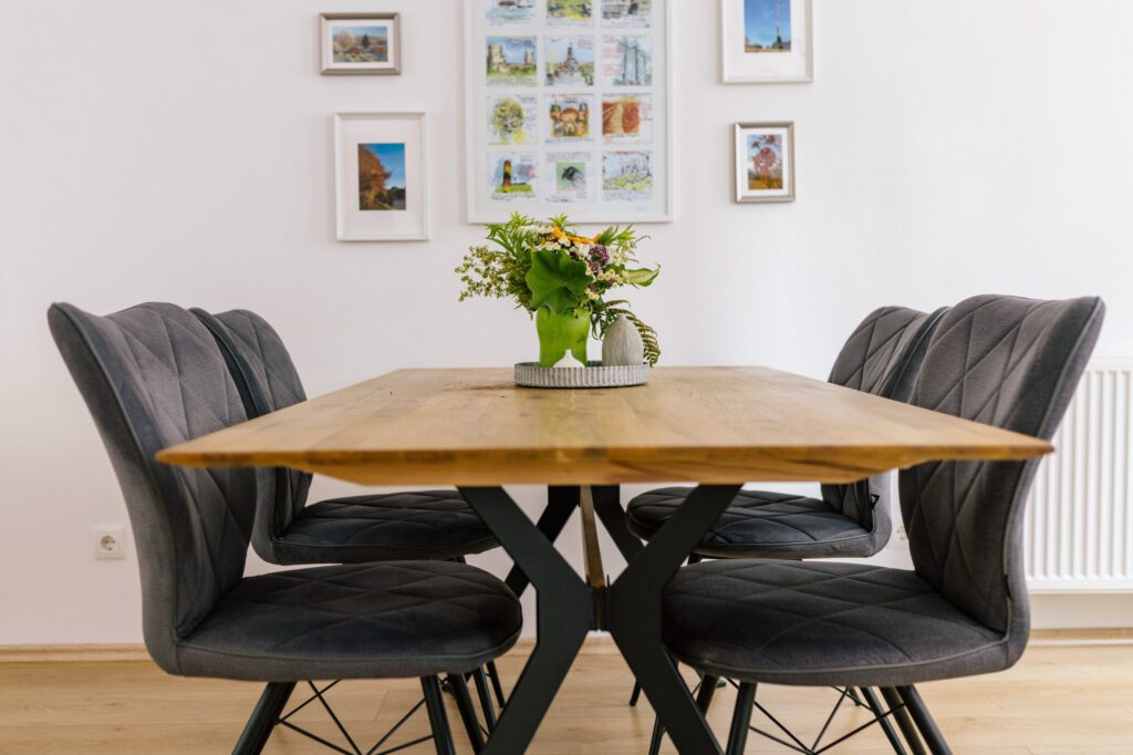 Festlich gedeckter Esstisch mit Blumenstrauß vor der Bilderwand in der Ferienwohnung Alte Pfarrgasse 5