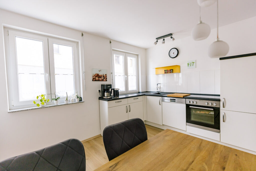 Helle Küche der Ferienwohnung Alte Pfarrgasse 5 mit Backofen, Kaffeemaschine und zwei Fenstern zum Hof